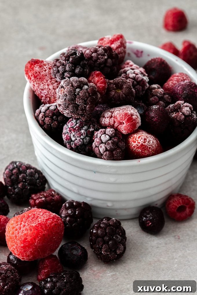 Close up shot of a white bowl of frozen berries, emphasizing the beauty and utility of frozen fruit