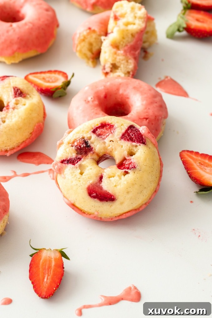 A close-up of a glazed Baked Strawberry Doughnut, showing the hidden strawberry pieces