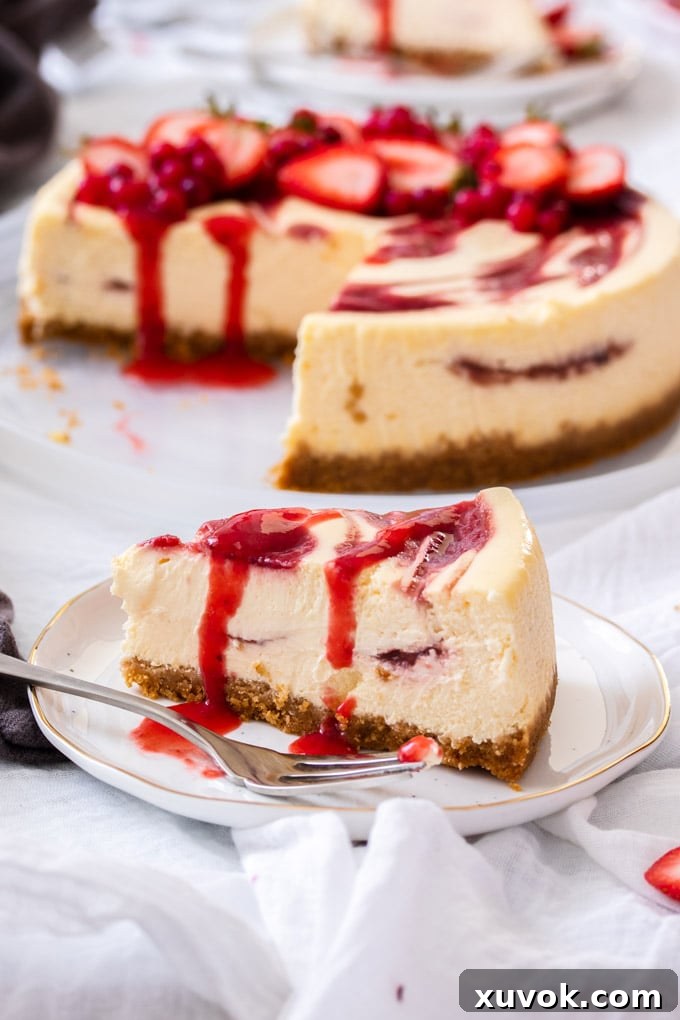 A perfectly sliced strawberry swirl cheesecake on a pristine white plate, with the rest of the beautifully swirled cheesecake visible in the background.