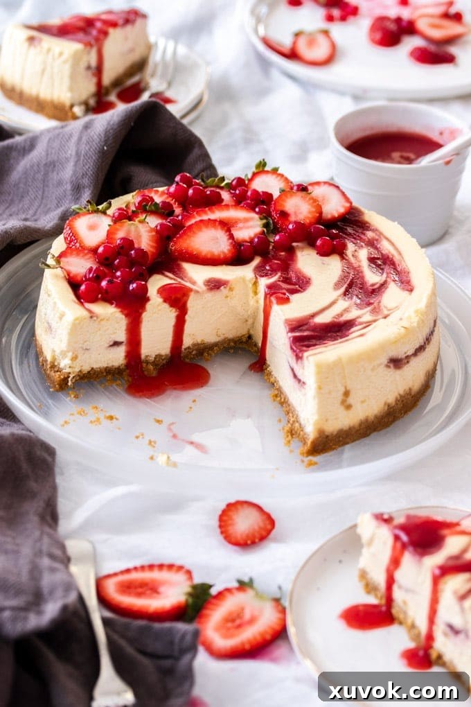 A pristine white plate holding a strawberry swirl cheesecake with one quarter elegantly sliced and removed, revealing its creamy, swirled interior.
