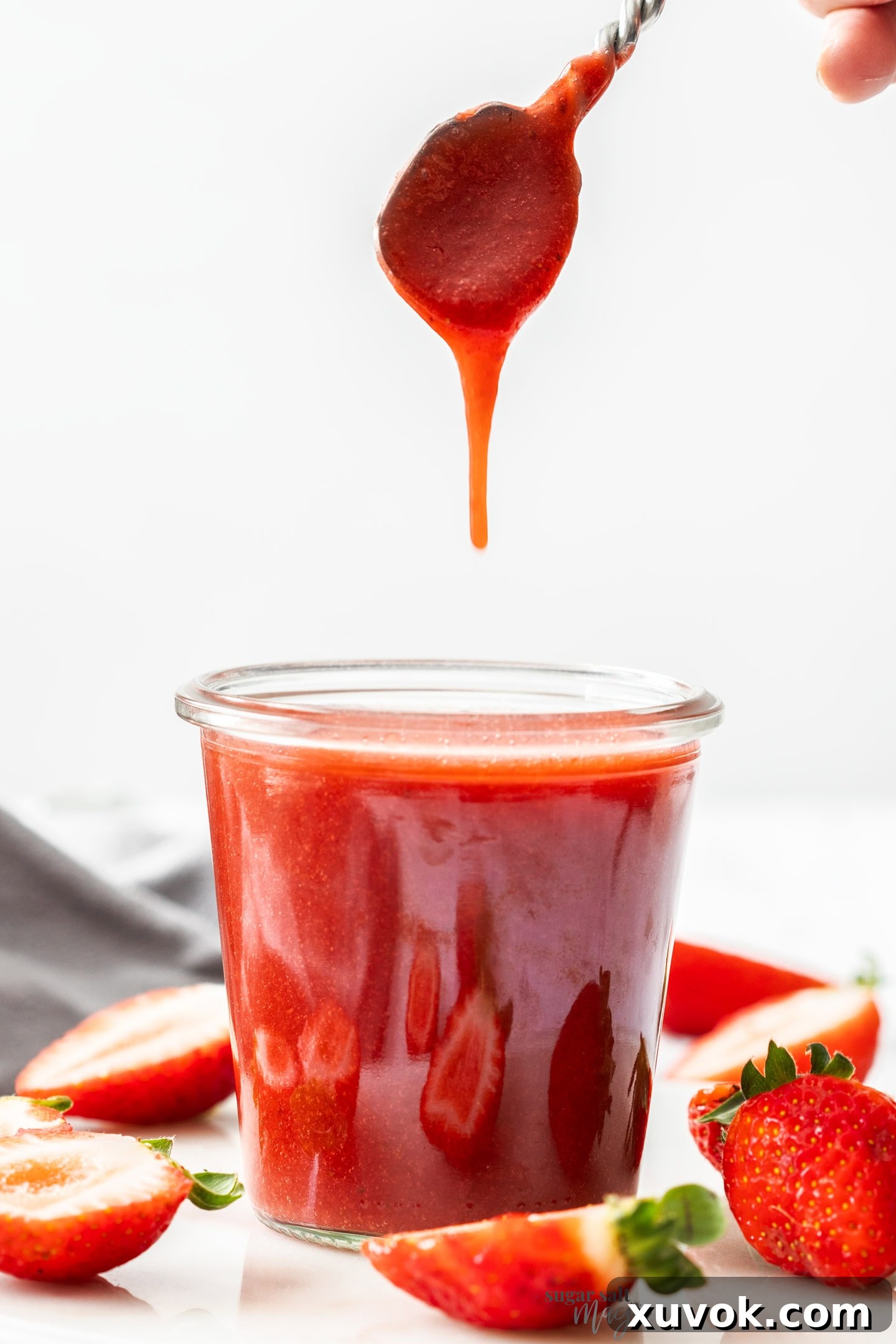 Strawberry sauce dropping off a spoon into a pot.