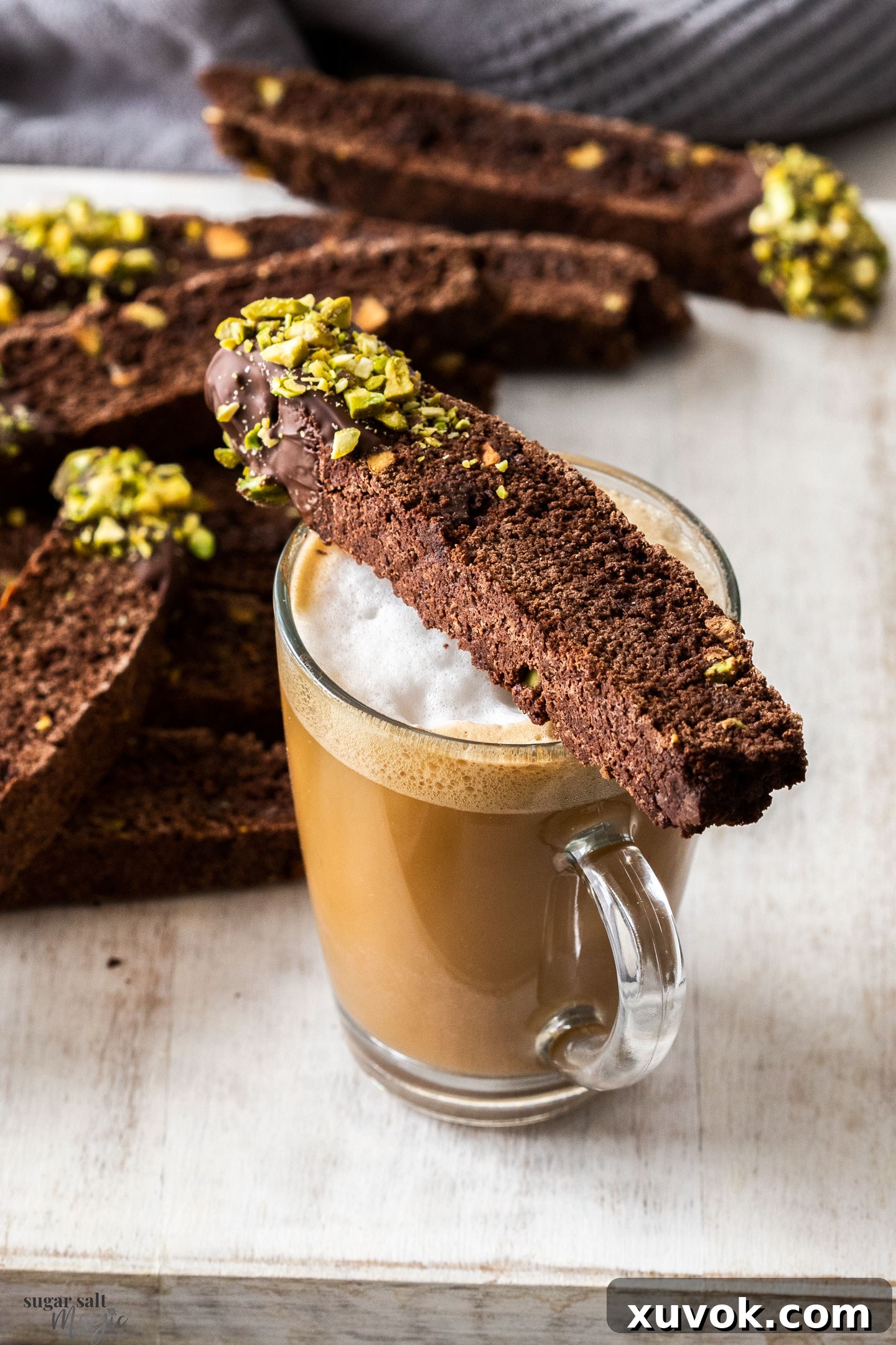 A chocolate biscotti sitting on a cup of coffee.
