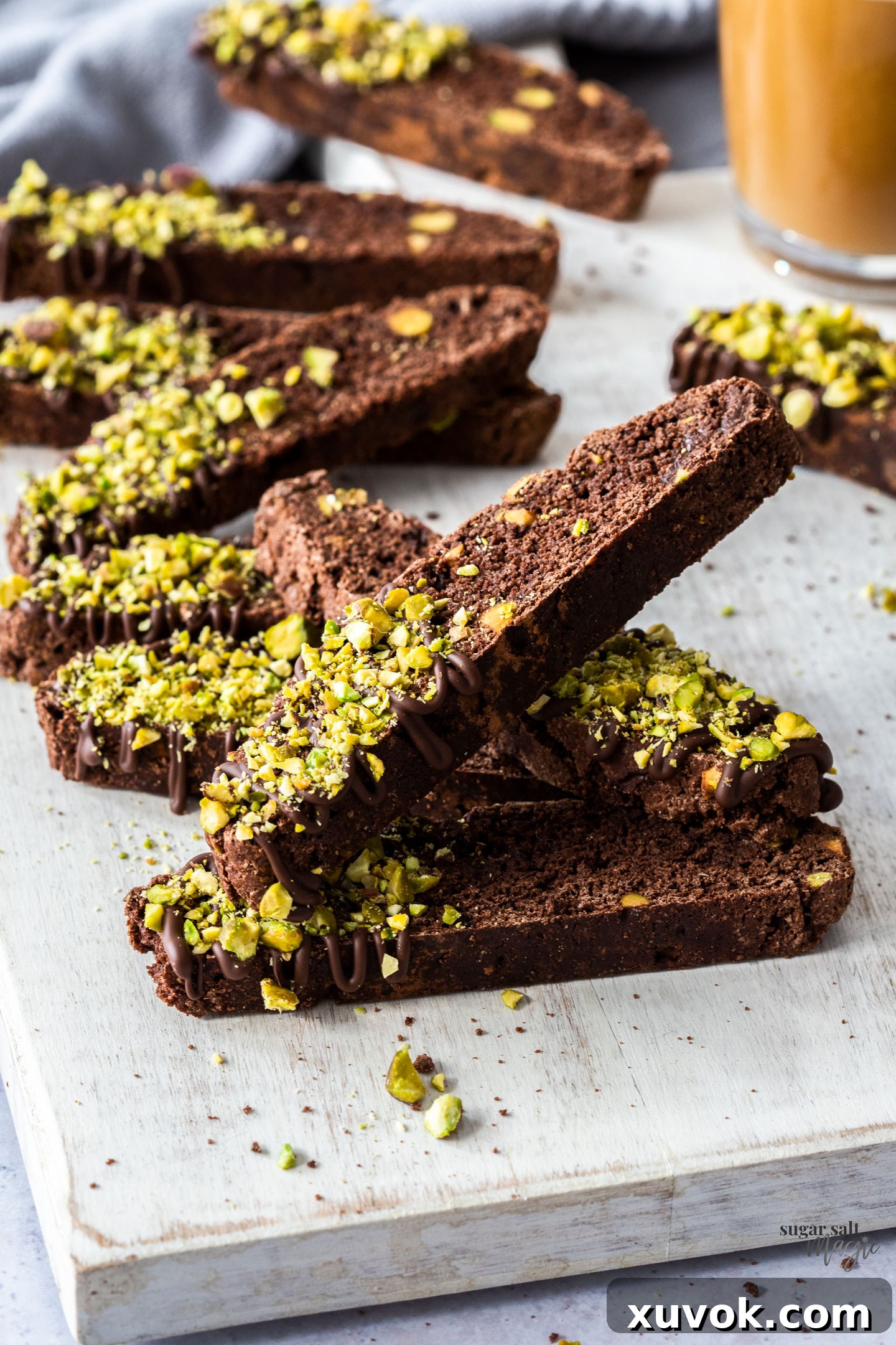 A pile of chocolate biscotti with pieces of pistachio.