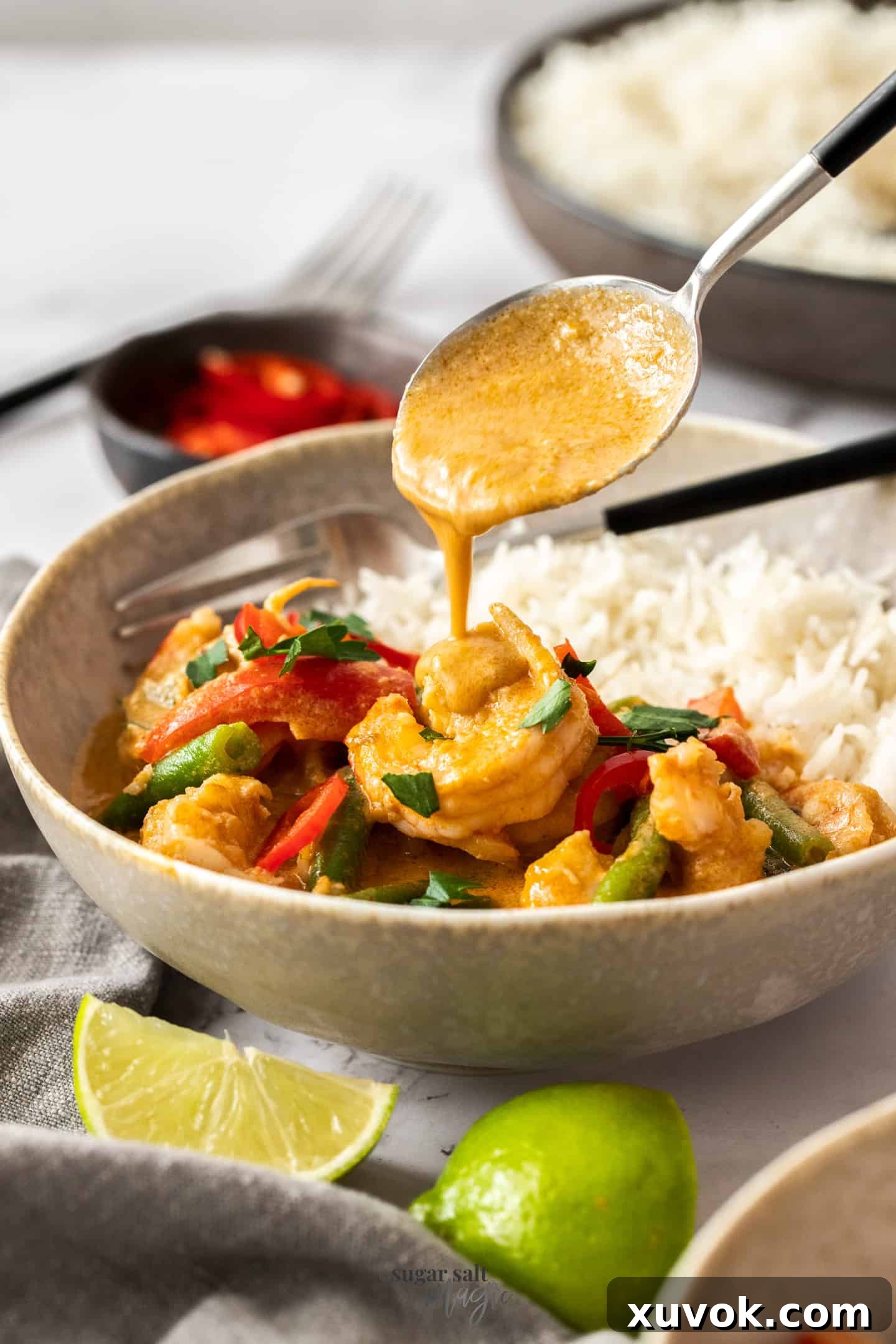 Sauce being poured over prawns in a bowl with rice.