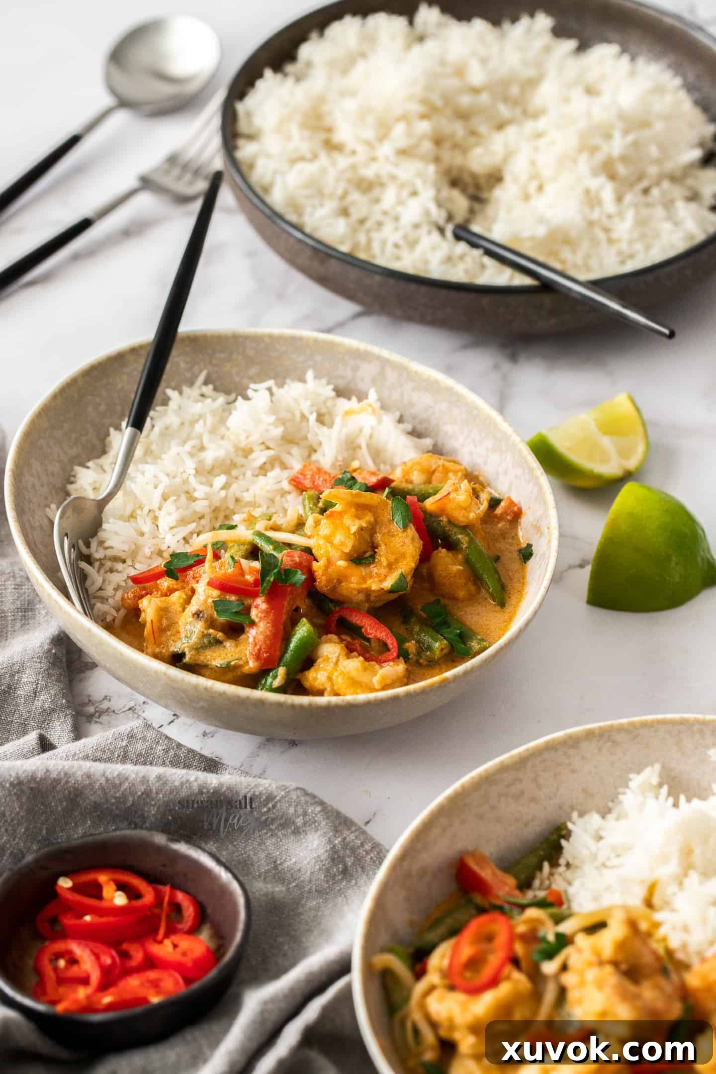 A bowl with rice and prawn curry with a bowl of rice in the background.