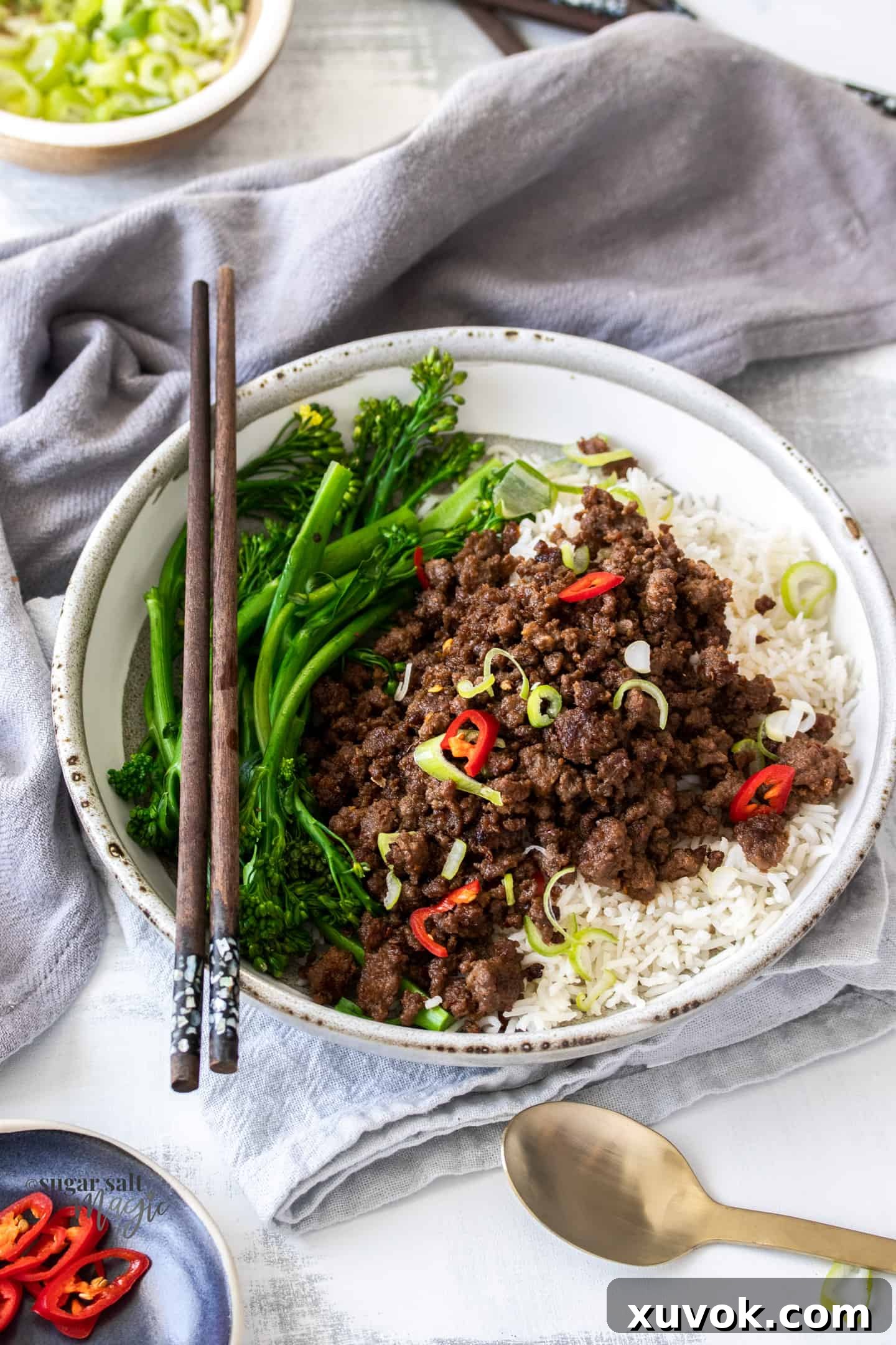 Top down view of a stylish grey bowl generously filled with fluffy steamed rice and topped with a savory mound of crispy stir-fried Asian ground beef.