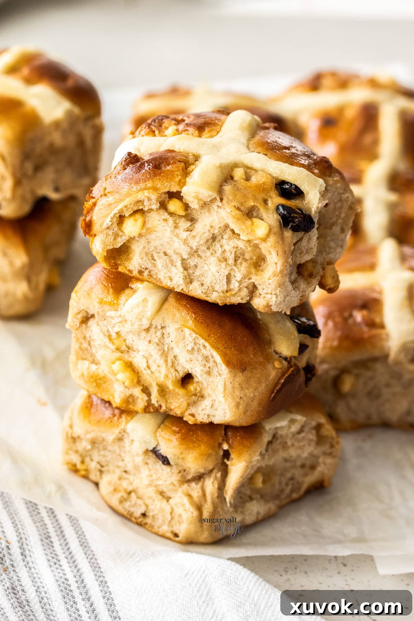 A stack of three perfectly baked Cranberry White Chocolate Hot Cross Buns, showing their soft texture and the cranberries and white chocolate peeking through.