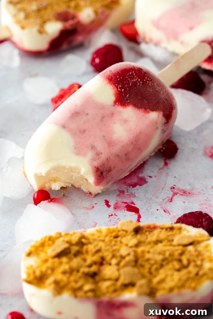 A closeup of a strawberry cheesecake ice cream bar with a bite taken out, showing the layers of strawberry swirl and creamy cheesecake base.