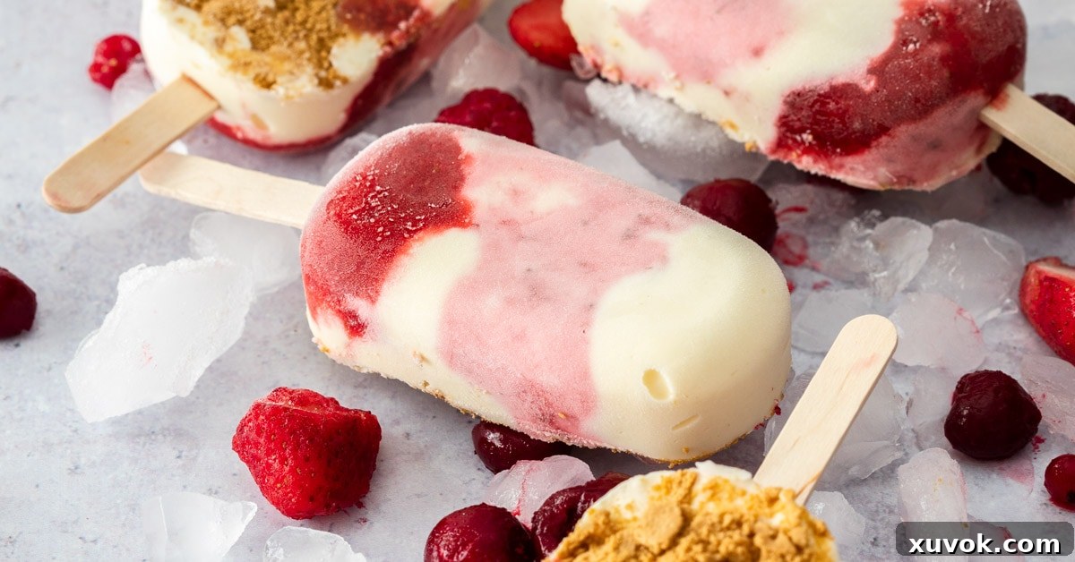 Closeup of a Strawberry Cheesecake Ice cream bar surrounded by ice and berries, showcasing the creamy texture and strawberry swirl.