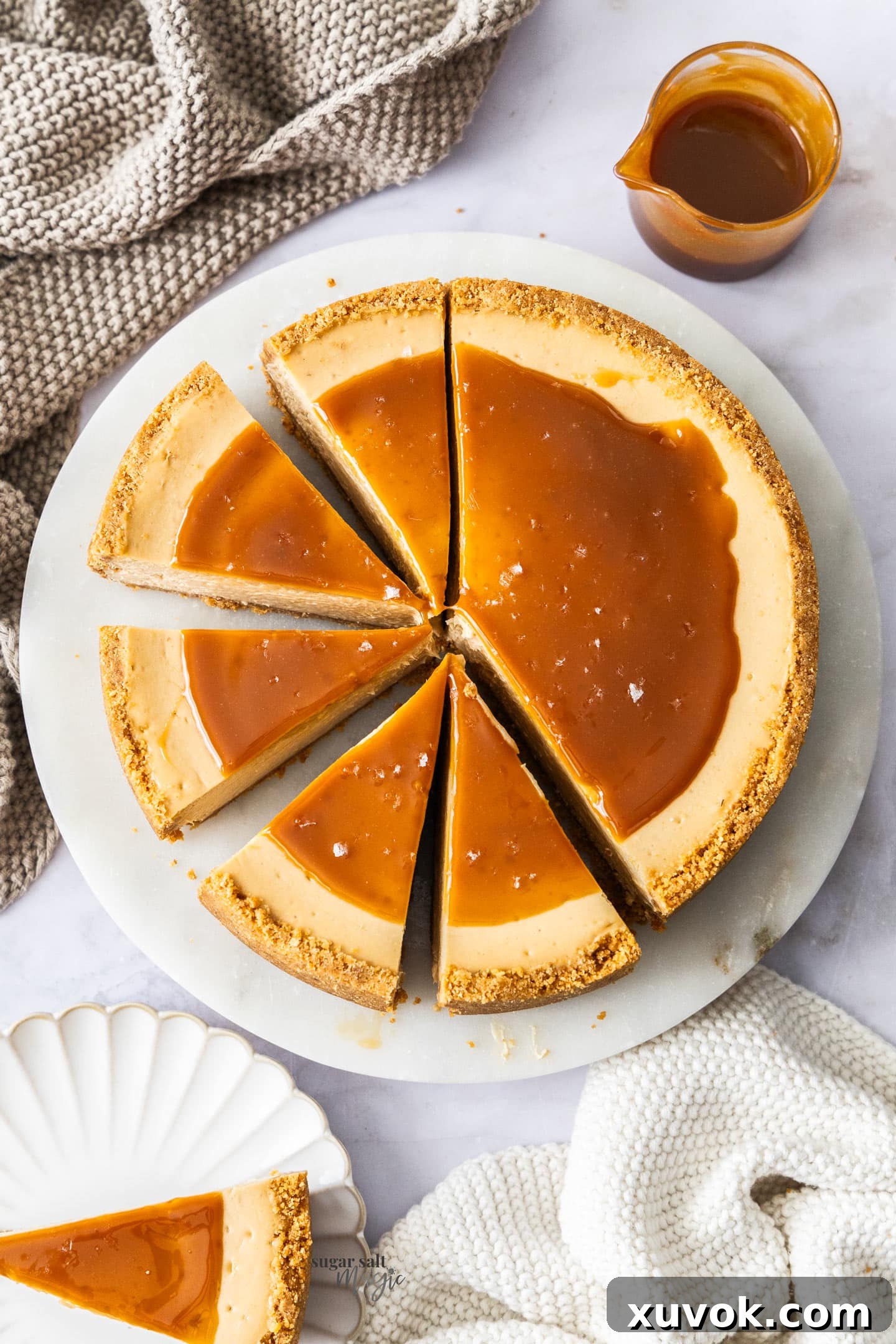 Top-down view of a whole baked caramel cheesecake with five slices already cut, showcasing its smooth texture and golden-brown crust.