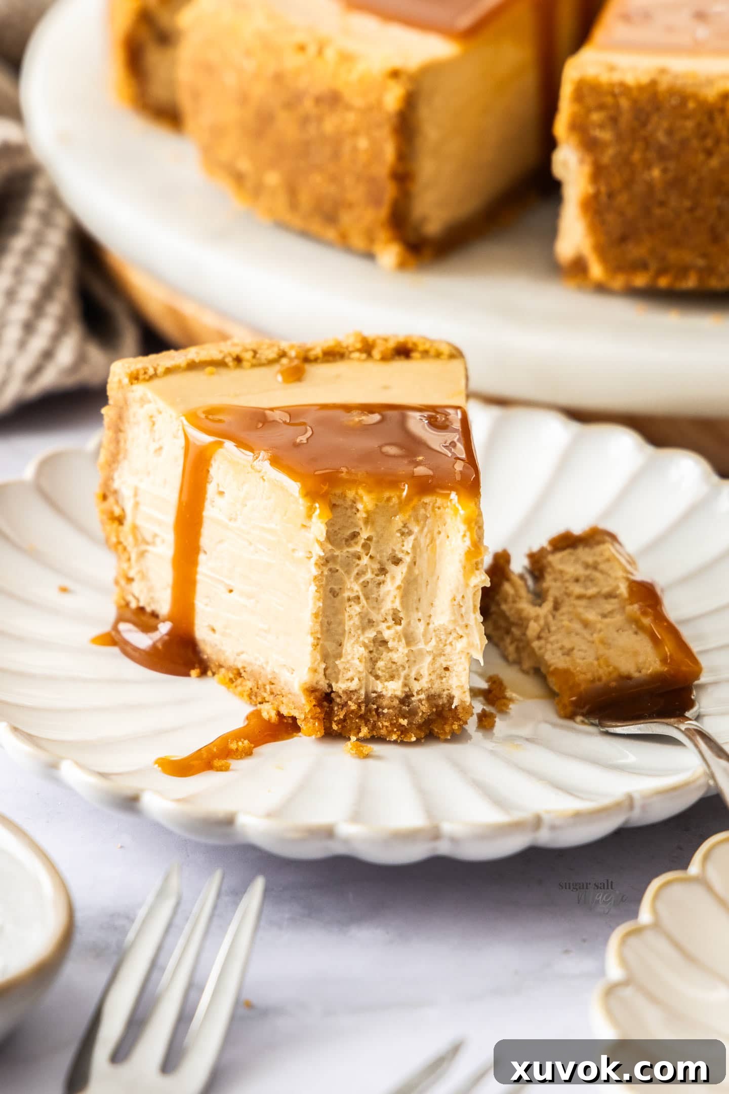 A delectable slice of caramel cheesecake on a white plate, with a fork taking a bite, showing its rich, dense texture and caramel drizzle.