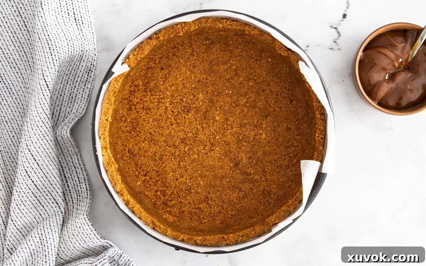 A perfectly formed cookie crust pressed into an 8-inch springform pan, ready to be filled with cheesecake batter.