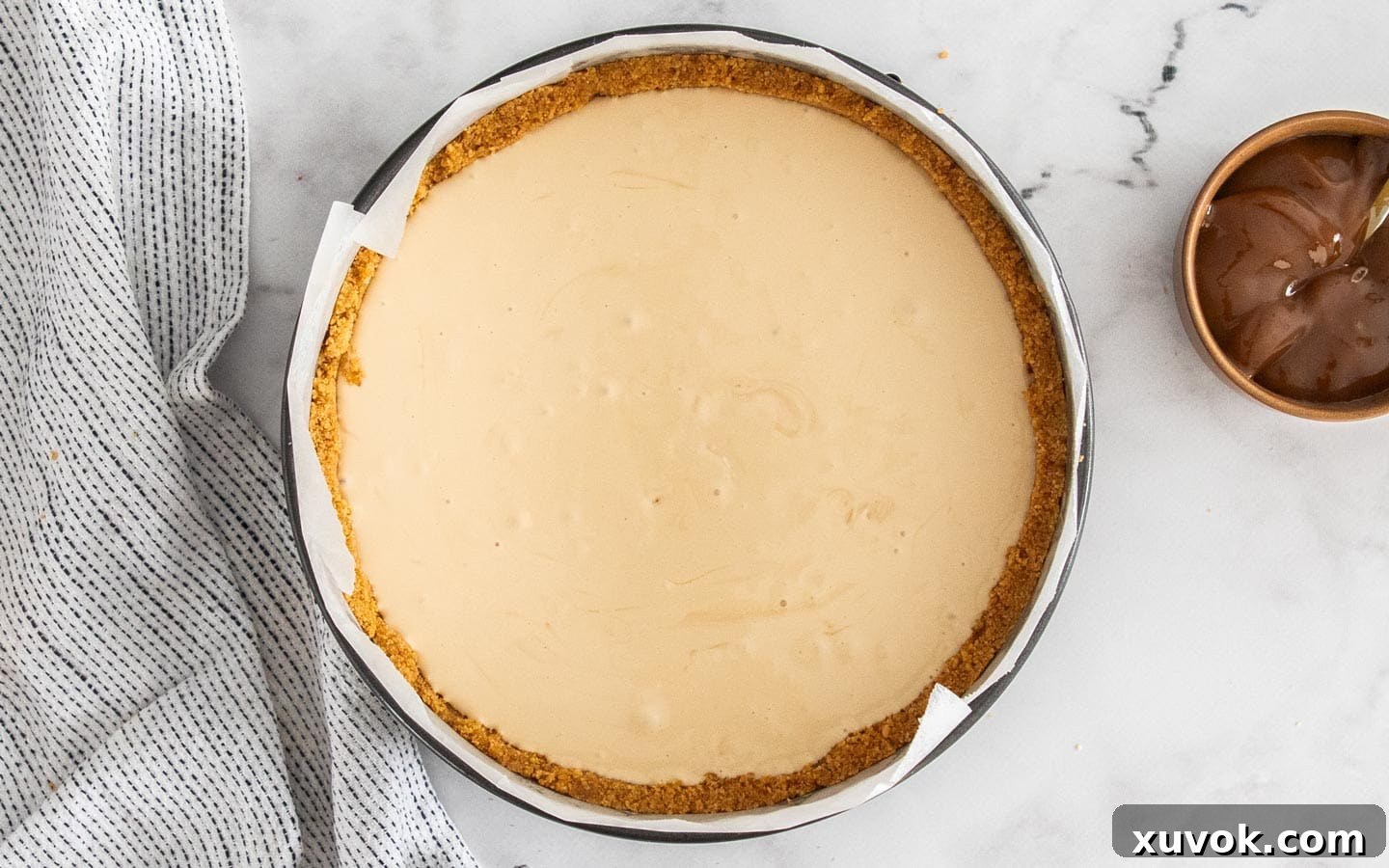The creamy caramel cheesecake filling freshly poured into the crisp cookie shell within the springform pan, ready for baking.