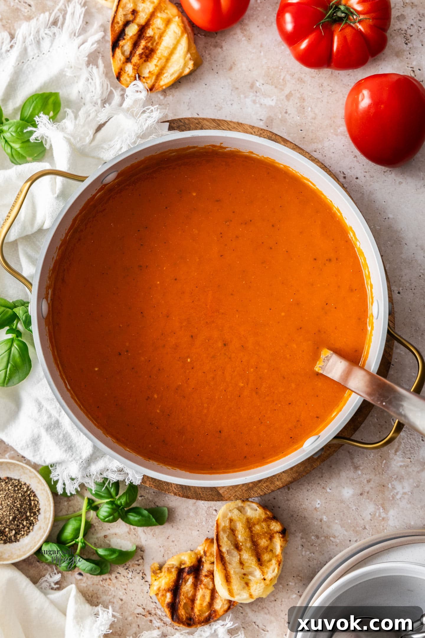 A top-down view of a large Dutch oven filled with simmering, perfectly smooth roasted garlic tomato soup.