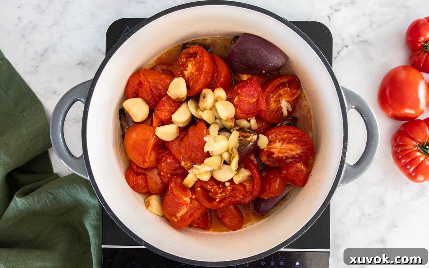The roasted tomatoes, onions, and squeezed garlic cloves have been transferred to a Dutch oven, ready for blending.