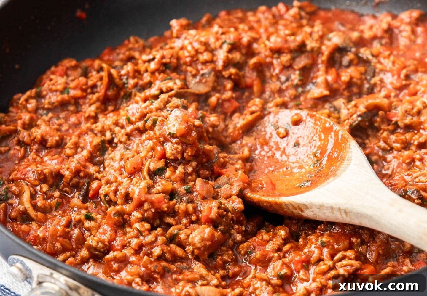 The meat sauce simmering in a frying pan, thick and richly colored, ready for layering.