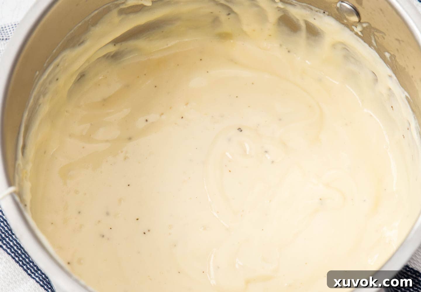 The final, perfectly smooth and creamy béchamel sauce in a saucepan, ready for assembly.