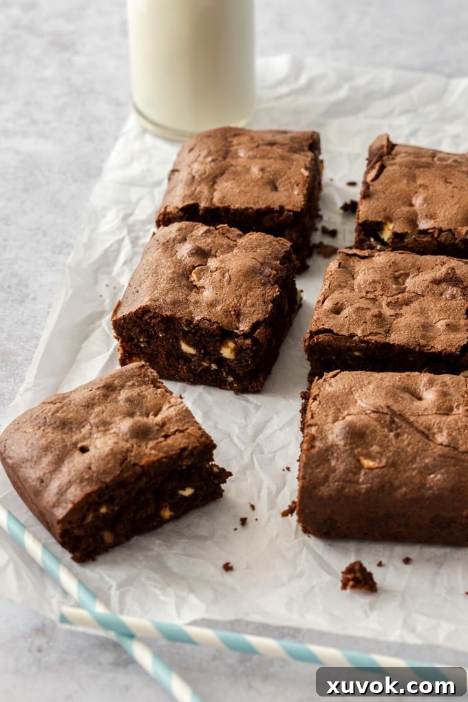 6 brownies sitting on a sheet of baking paper with a jug of milk in the background