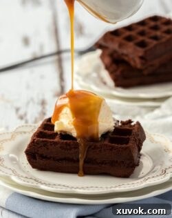 A delicious waffle brownie topped with a scoop of ice cream and drizzled caramel sauce, ready to be enjoyed.