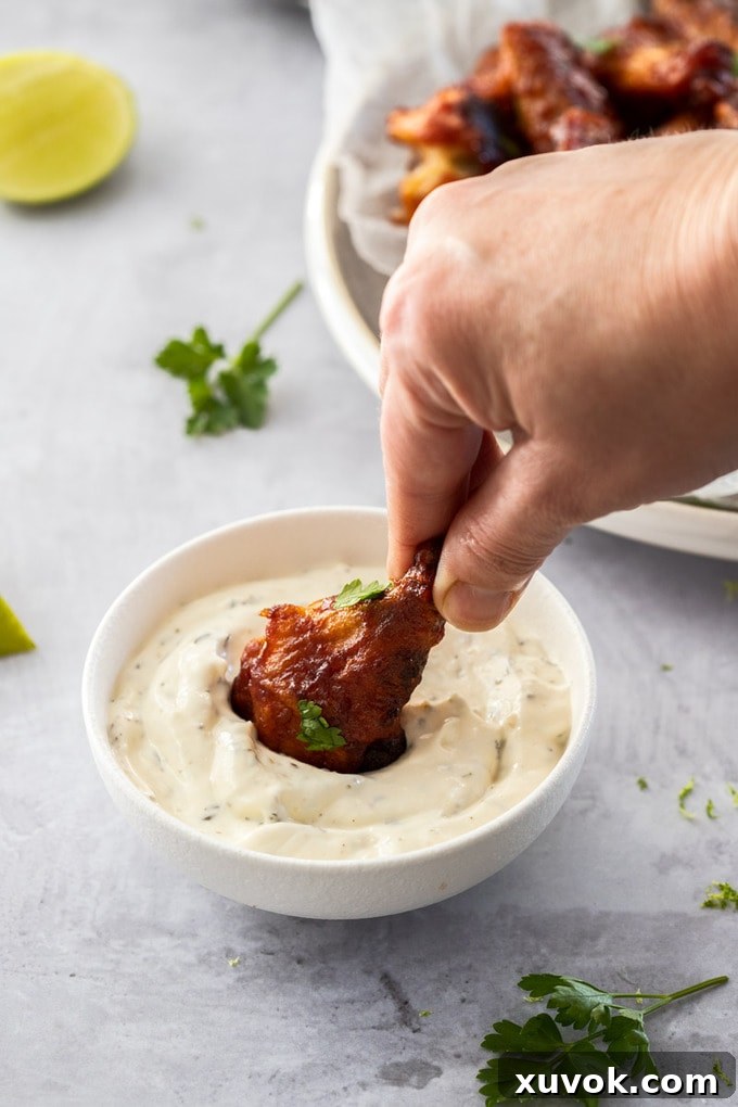 A chicken wing being dipped into a white bowl of creamy homemade ranch dip.
