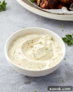 A small white bowl filled with ranch dip on a concrete surface, ready for serving.
