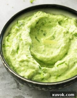 Close-up view of a black bowl brimming with freshly made avocado cream sauce.