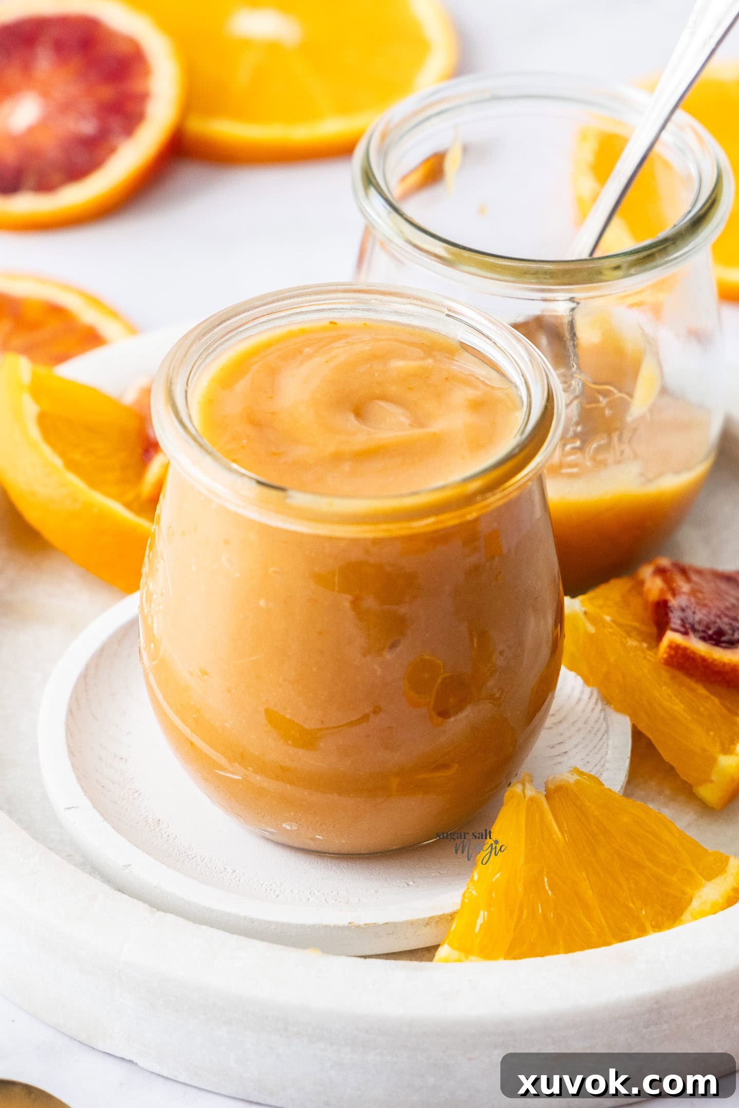 A beautiful glass jar filled to the brim with homemade blood orange curd, showcasing its peachy hue.