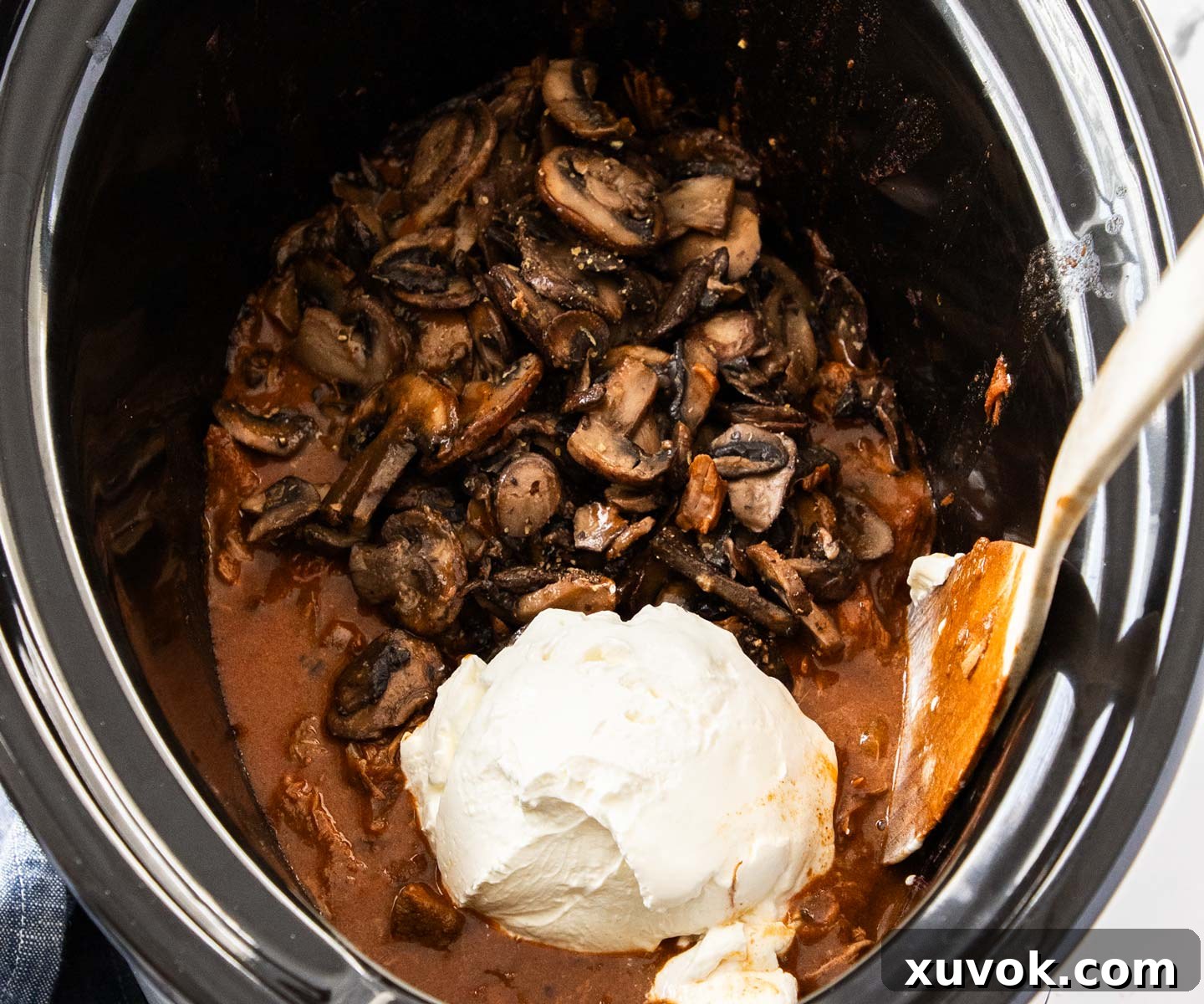 The mushrooms and sour cream added to the top of the beef stroganoff, ready to be stirred in.