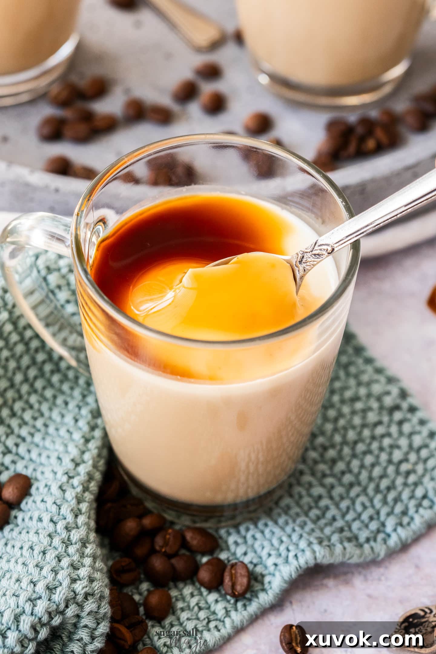 A spoon digging into coffee panna cotta, showcasing its creamy layers and smooth texture.