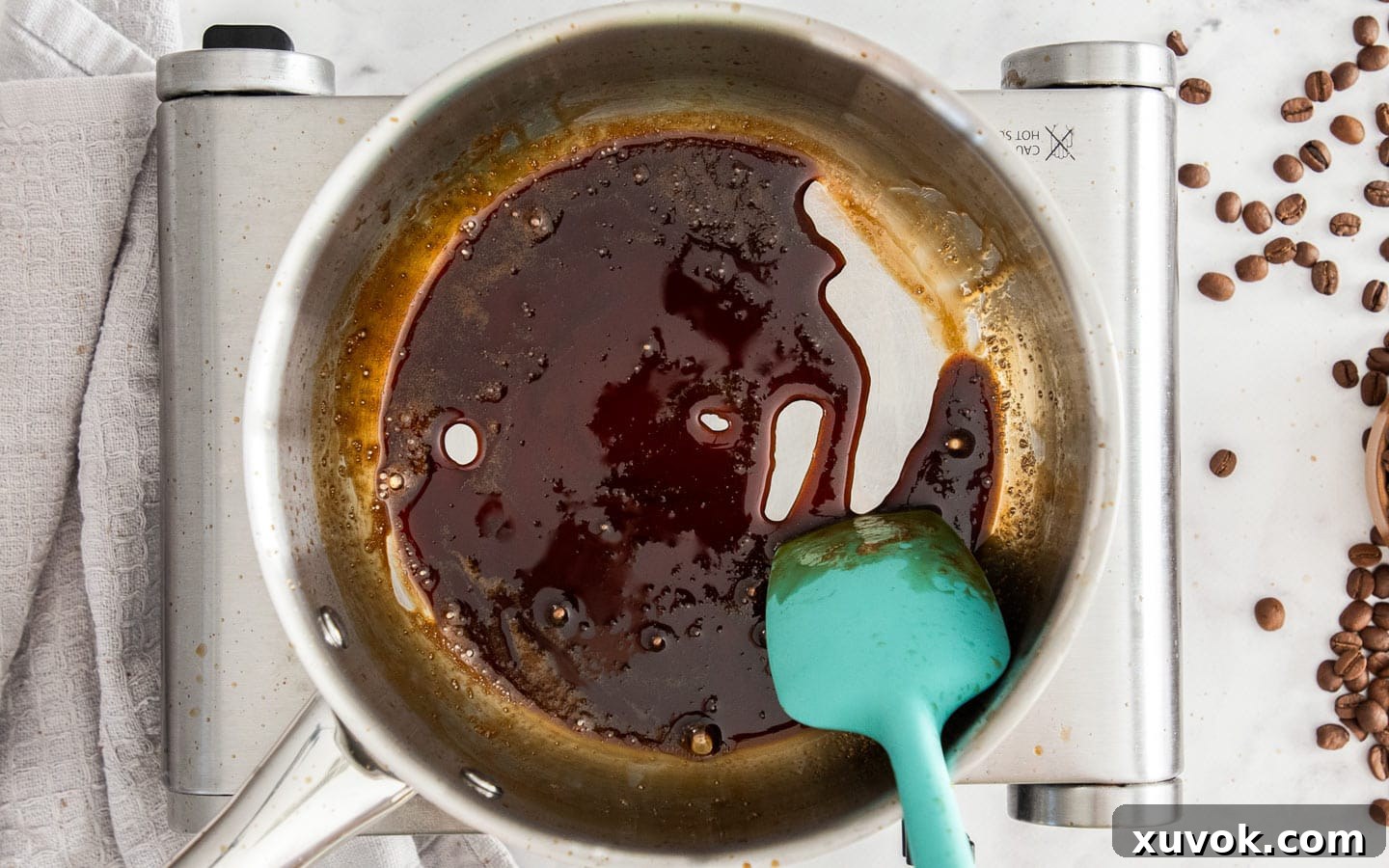 The coffee syrup, now thickened to a glossy, syrupy consistency in the saucepan.
