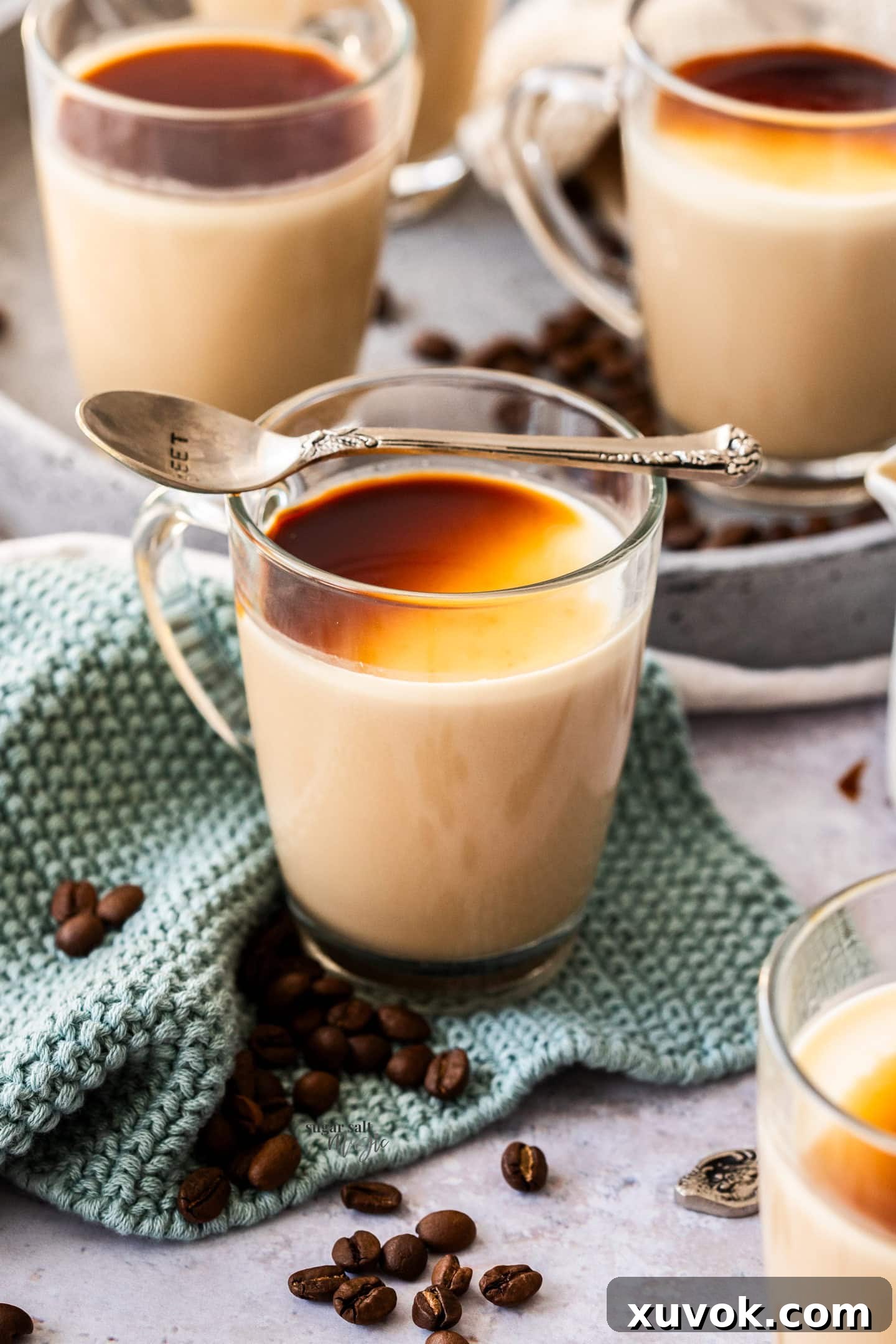 A beautifully presented glass of espresso panna cotta, topped with coffee syrup, with a spoon resting invitingly on top.