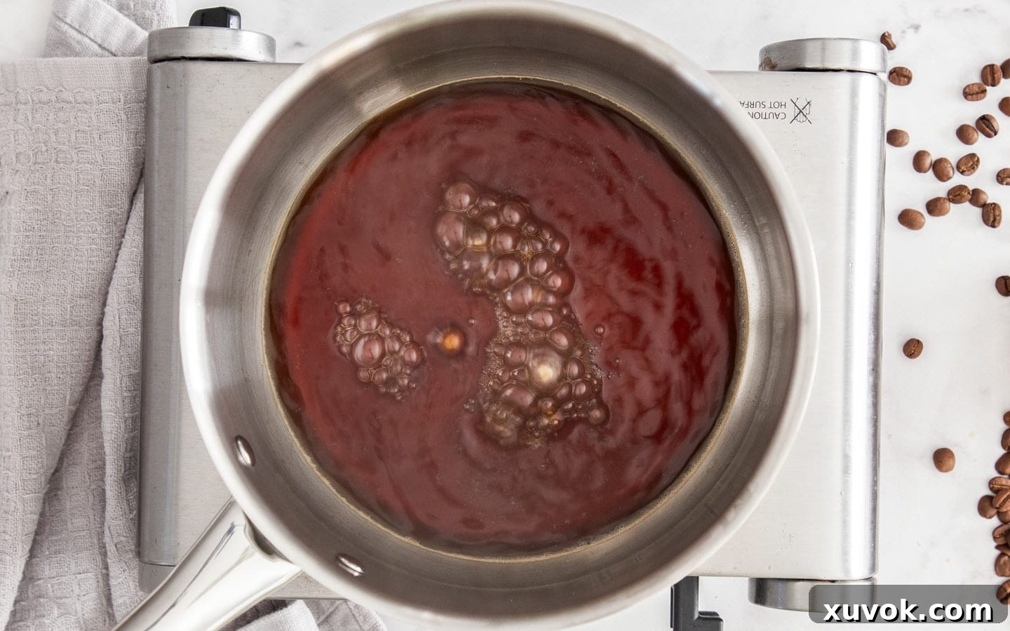 Close-up of the coffee syrup gently simmering in a saucepan on the stovetop.