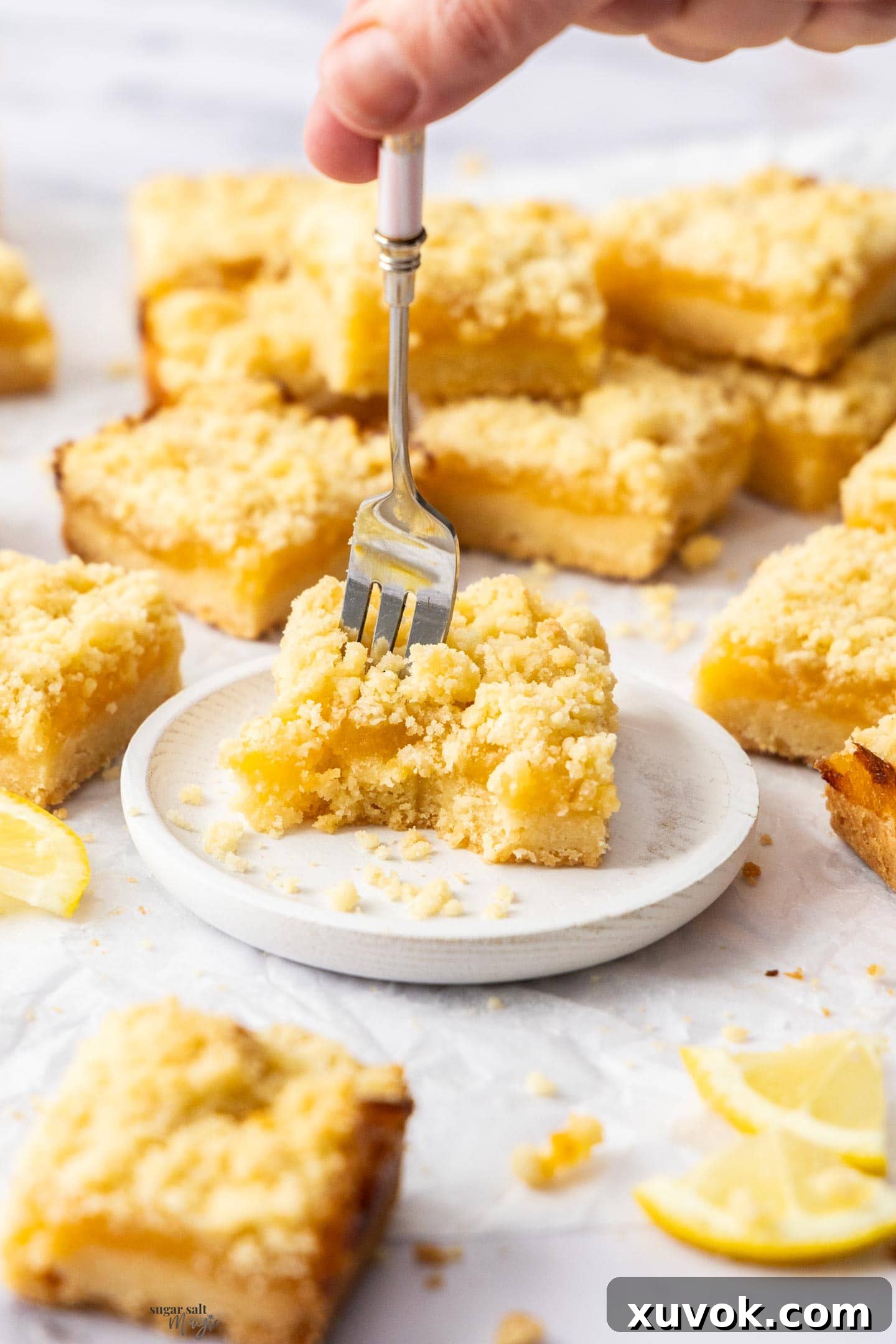 A fork digging into a lemon curd bar on a small plate.