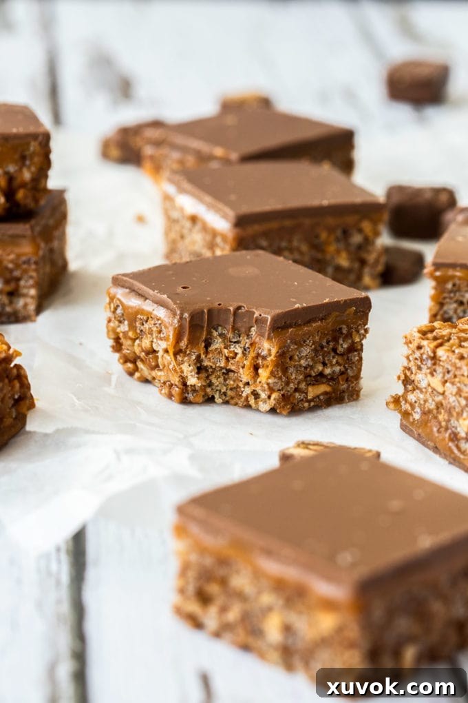 A delicious slice of Snickers crispy cake with a bite taken out, revealing the crispy base, chewy caramel, and chocolate layers.