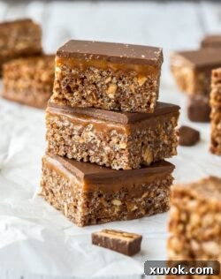 A stack of 3 snickers rice krispie treats on a sheet of white baking paper