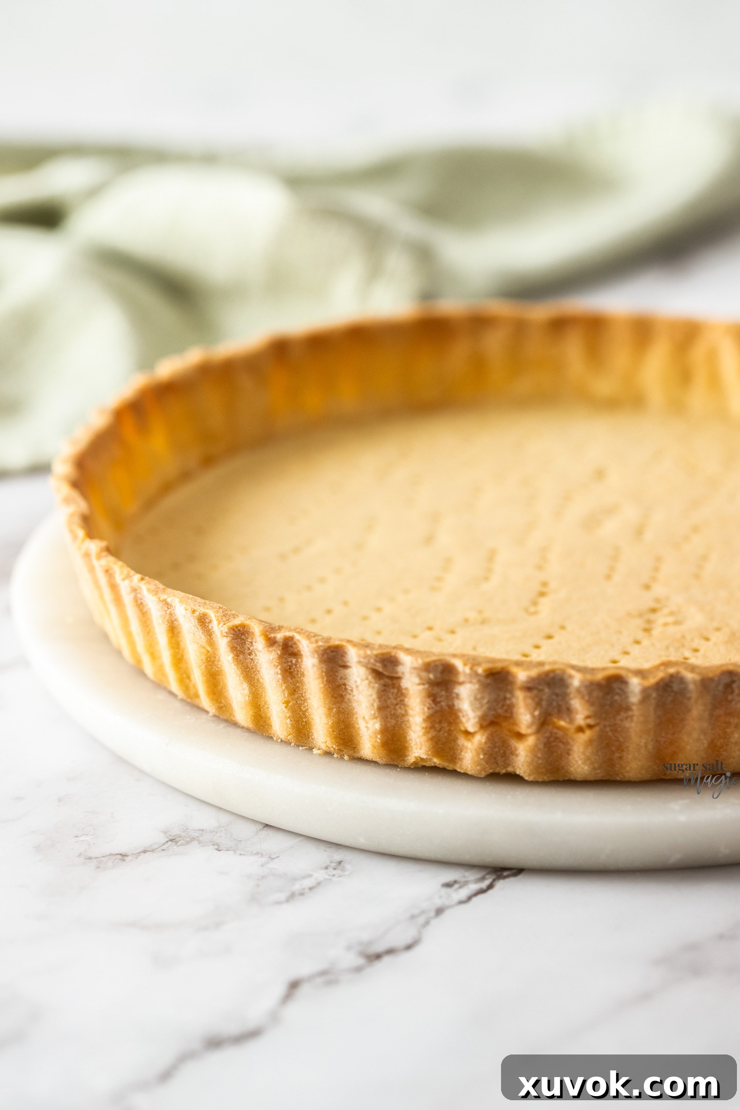 A tart shell shown at an angle, revealing its crisp, golden-brown edges.