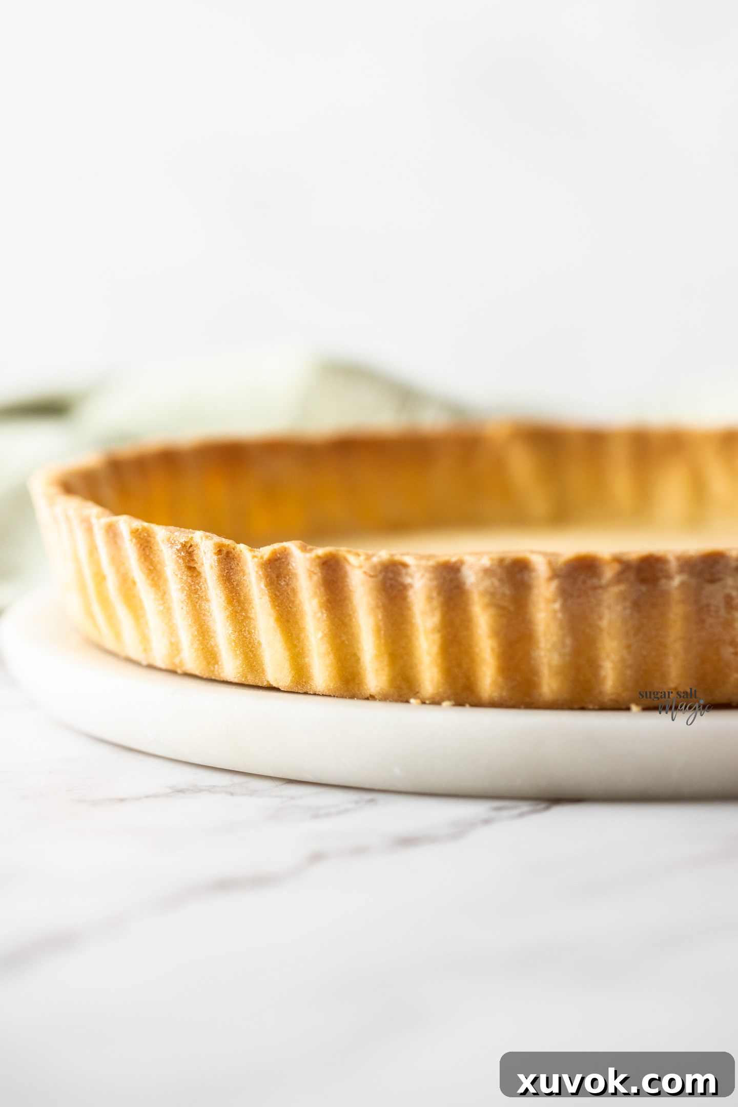 Close-up view of the delicate fluted side of a baked shortcrust pastry tart shell.