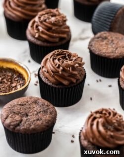 A batch of double chocolate cupcakes on a white marble surface.
