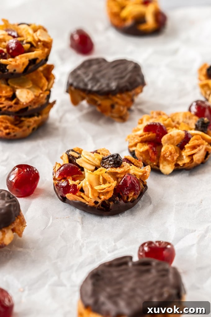 A cluster of beautifully golden Florentine cookies artfully arranged on white baking paper, surrounded by scattered glace cherries.