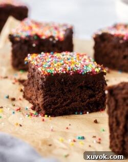 closeup of a piece of chocolate cake topped with sprinkles on a piece of brown parchment paper