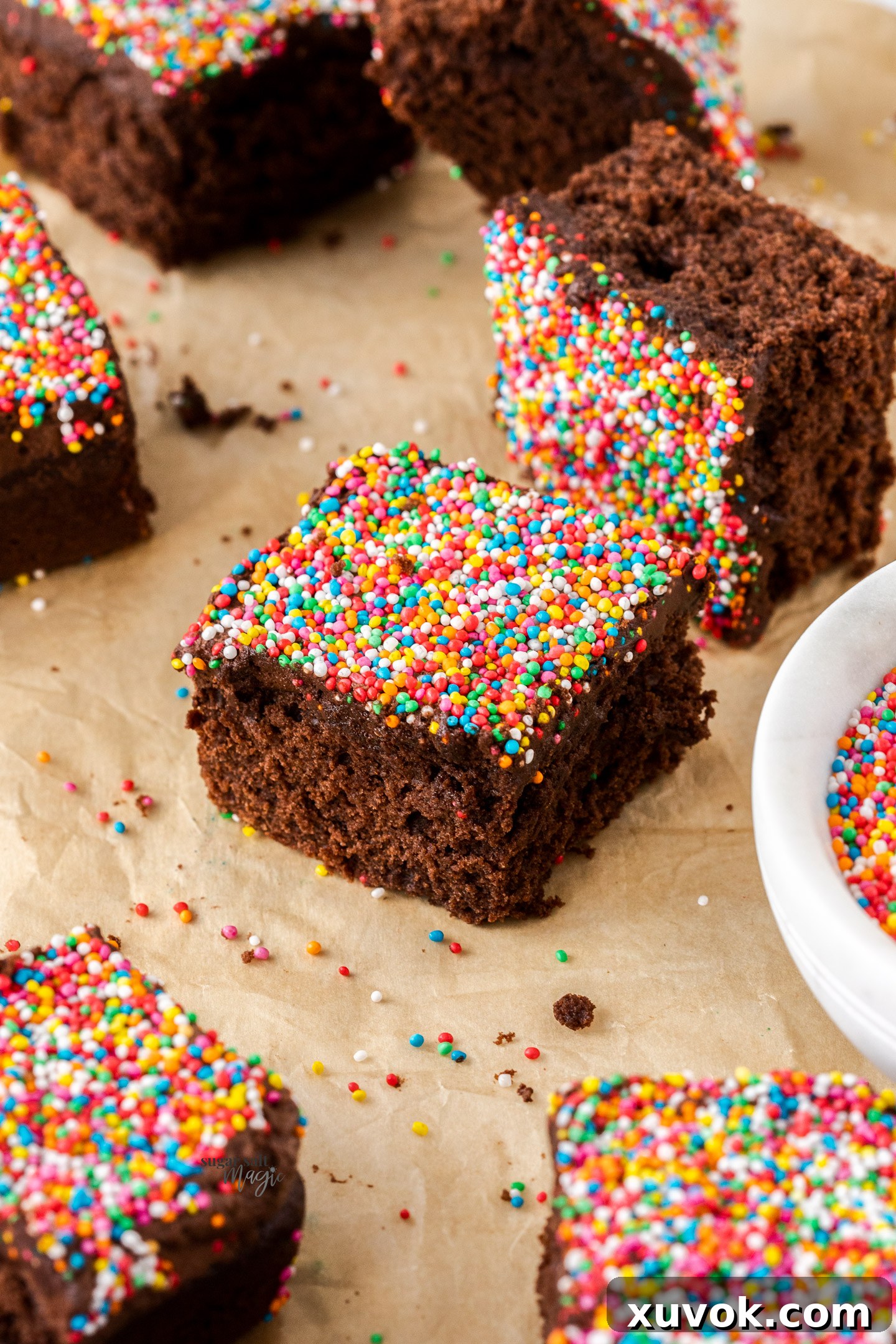 Close-up shot of multiple squares of one-bowl chocolate cake, beautifully covered in colorful sprinkles.