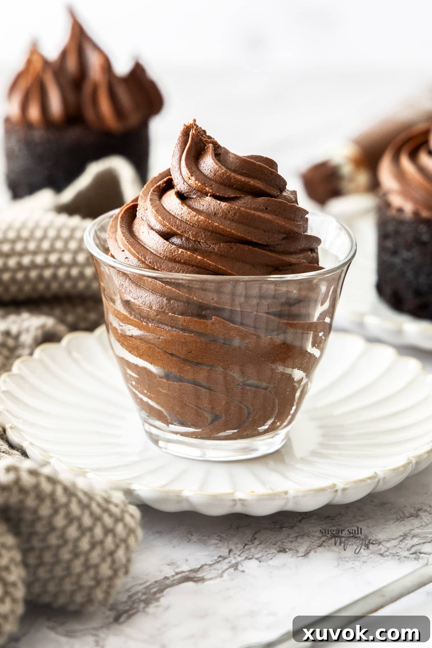 A glass filled with rich, glossy chocolate fudge frosting, ready to be used on desserts.