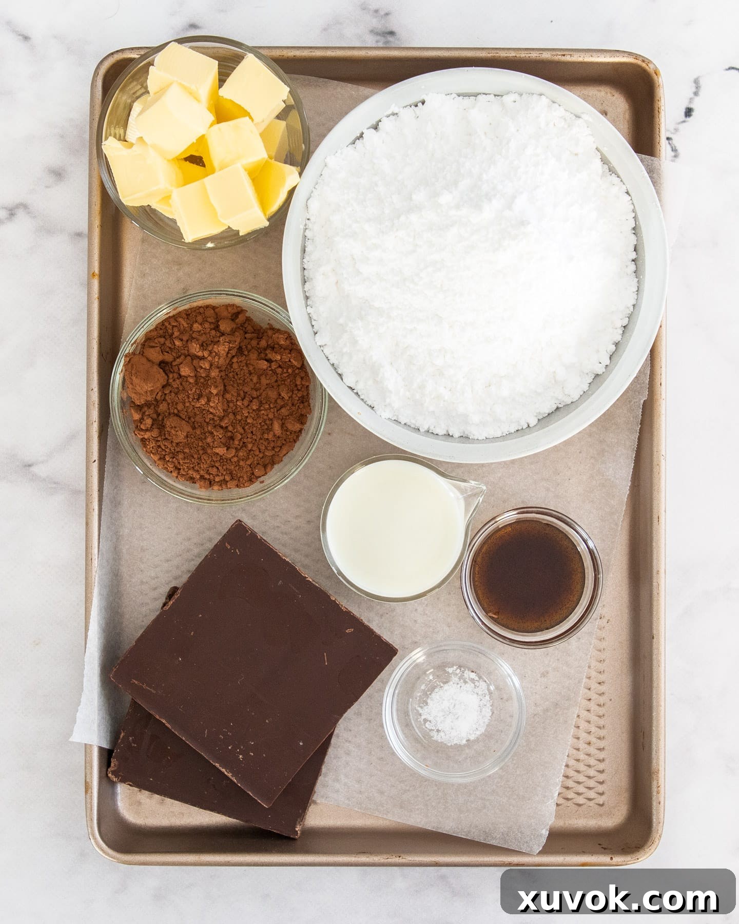 A selection of ingredients for chocolate fudge frosting, including butter, chocolate, and cocoa powder.