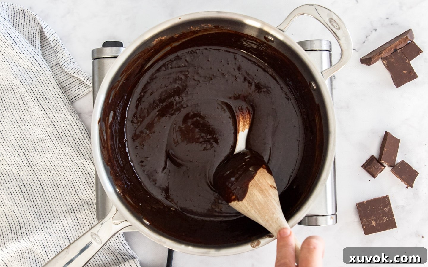 The smooth mixture of melted chocolate, butter, and cocoa powder in a saucepan.