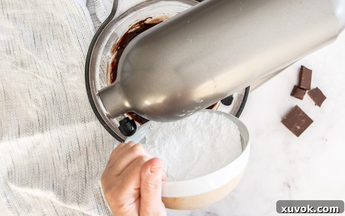 Icing sugar being added to the rich chocolate mixture in a mixing bowl.