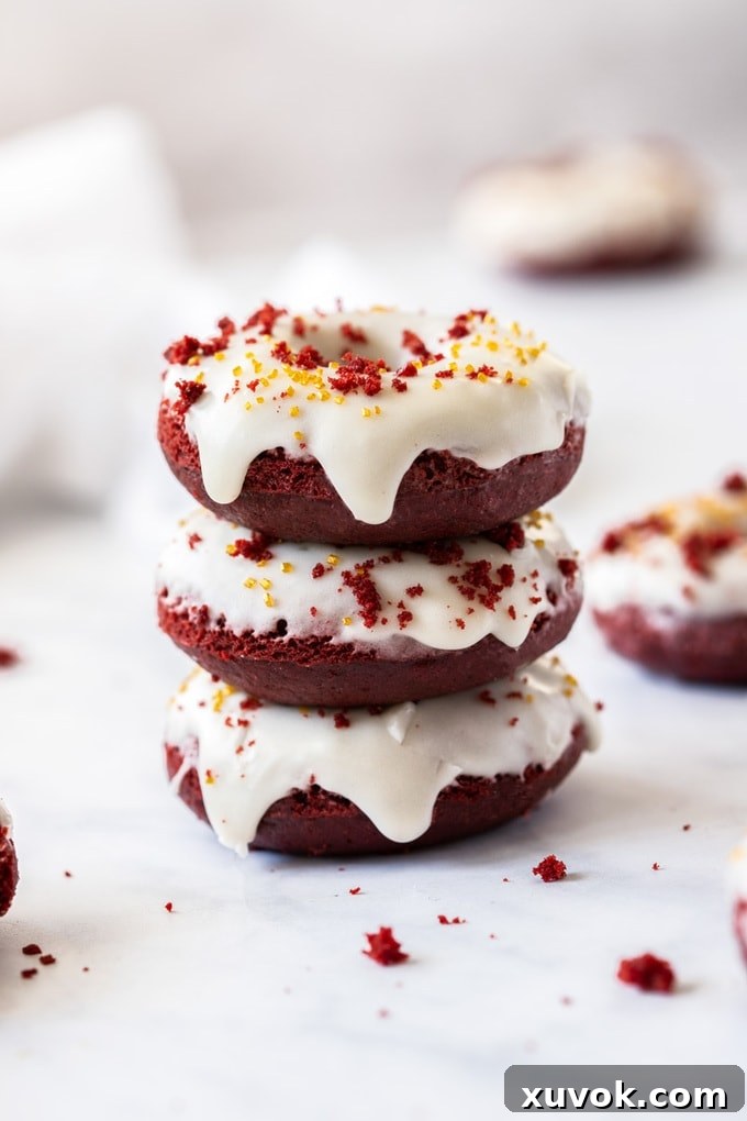 A stack of 3 red velvet donuts with white cream cheese glaze