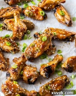 A batch of sticky, glossy honey soy chicken wings on a sheet of baking paper, ready to be served.