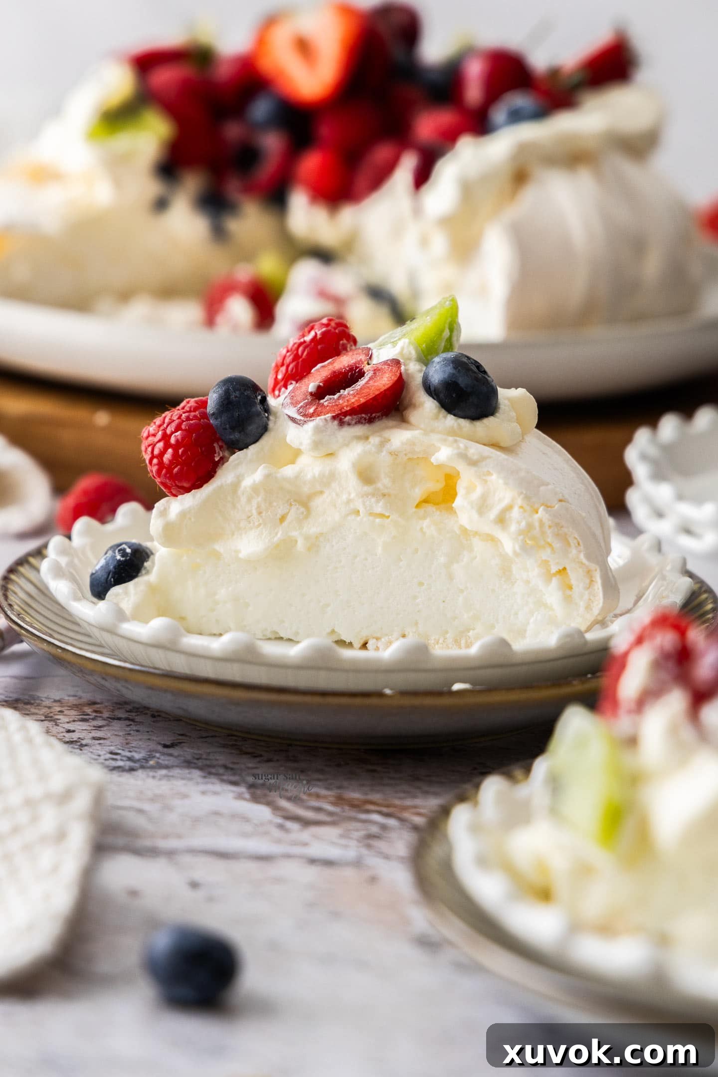 A perfectly sliced piece of pavlova on a dessert plate, showcasing its soft interior and fruit topping.
