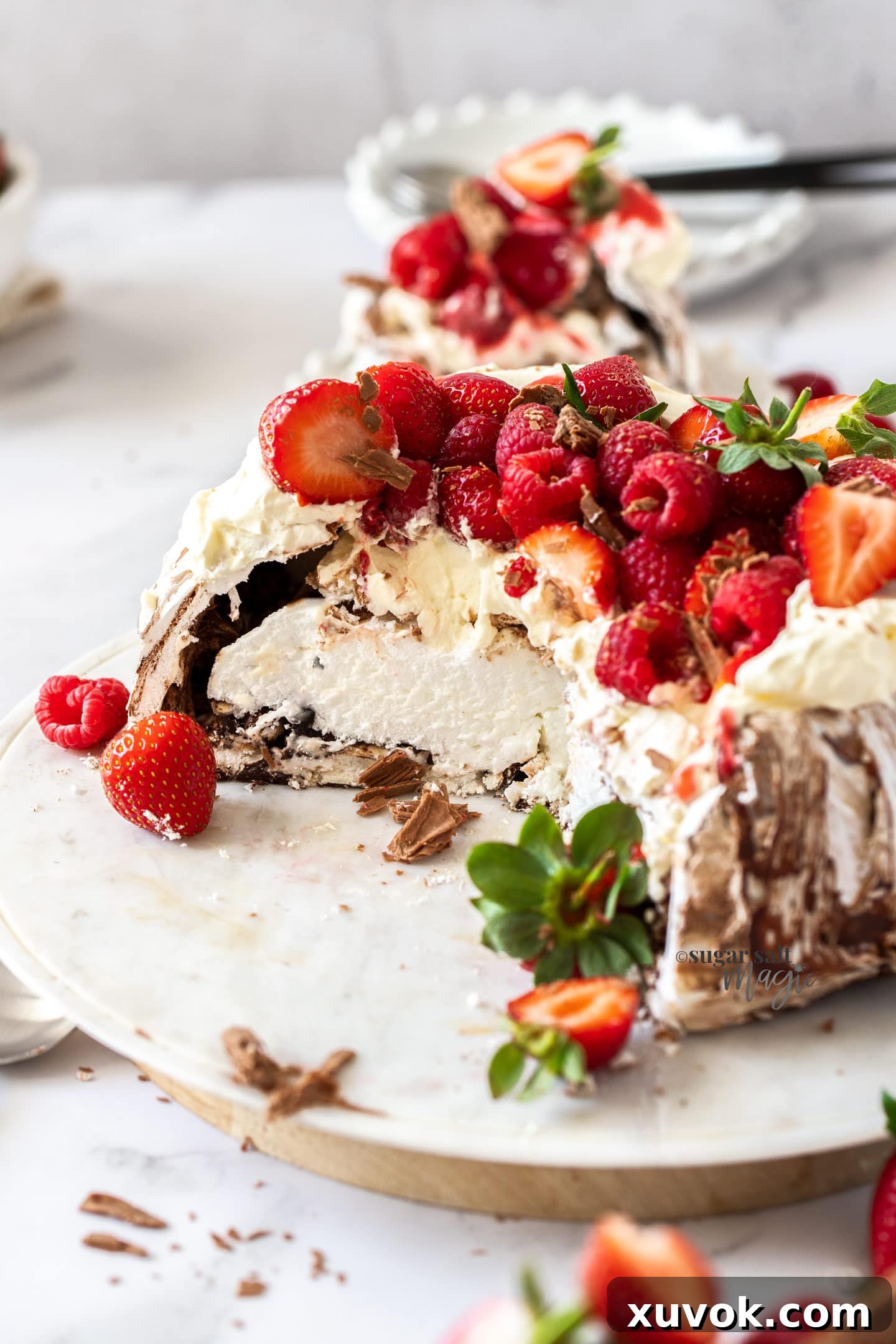 A delicious chocolate pavlova, adorned with whipped cream and fresh berries, cut open to reveal its rich interior.