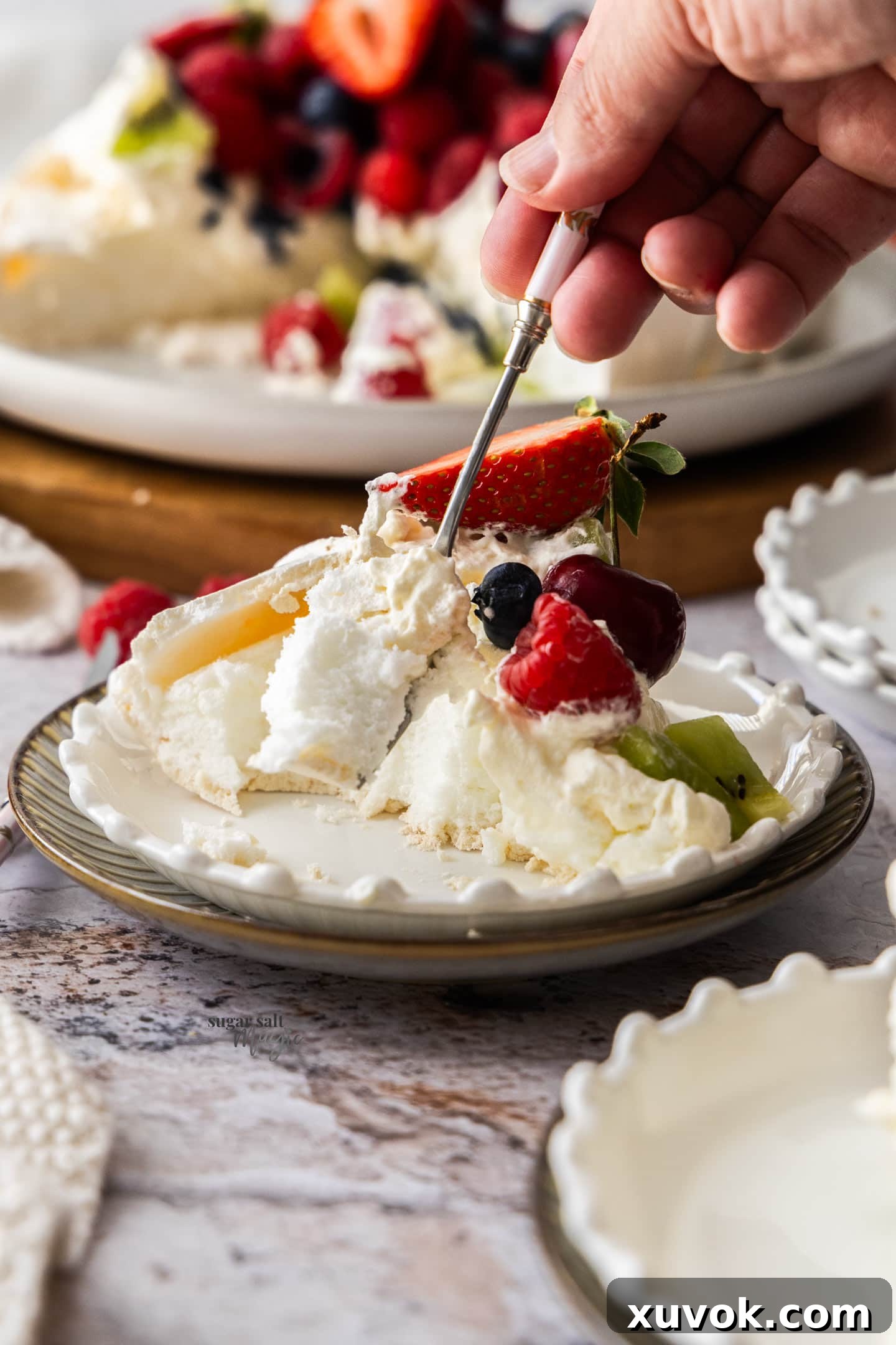A fork gently cutting into a slice of pavlova, revealing its soft, marshmallowy center and crisp shell.